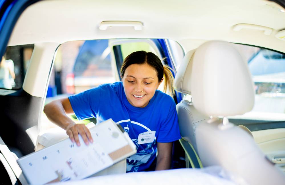 An Alumna unloading a student's car.